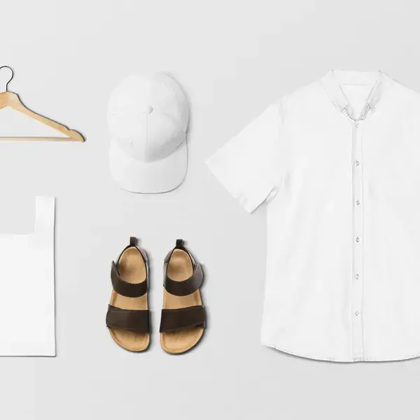 Flat lay of a white linen shirt with cap, sandals and tote